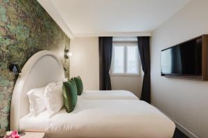 ein Hotelzimmer mit zwei Betten und einem Flachbildfernseher in der Unterkunft Hotel Prince Albert Opéra in Paris