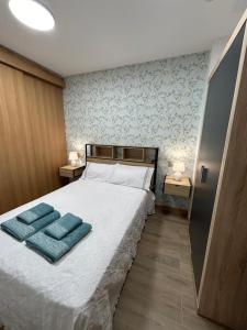 een slaapkamer met een bed met twee blauwe handdoeken erop bij Apartamentos Torres del Milladoiro in Amés +25 foto's
