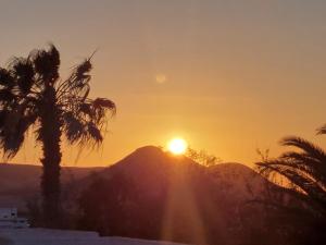 una puesta de sol sobre una montaña con palmeras en Studio with pool garden and open roof bathroom, en Lajares