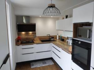 a kitchen with white cabinets and a black appliance at maison d'hôtes in Rouffiac