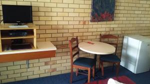 Habitación con mesa, sillas y TV. en Nambour Central Motel en Nambour