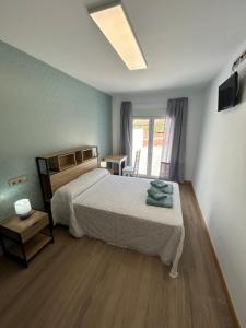 een slaapkamer met een bed, een tafel en een raam bij Apartamentos Torres del Milladoiro in Amés