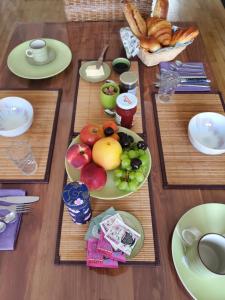 Ein Tisch, gedeckt mit einem Teller Obst und Brot in der Unterkunft Colibri in Rocquencourt