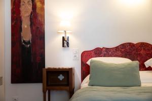 a bedroom with a bed with a painting on the wall at Oustau Camarguen Hôtel & Spa in Le Grau-du-Roi