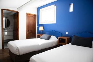 two beds in a room with a blue wall at Oustau Camarguen Hôtel & Spa in Le Grau-du-Roi