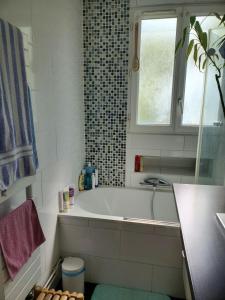 ein weißes Badezimmer mit Badewanne und Fenster in der Unterkunft Colibri in Rocquencourt
