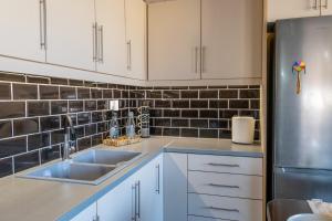 a kitchen with white cabinets and a stainless steel refrigerator at Evelina 5 in Lixouri