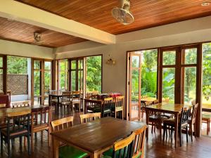 a restaurant with wooden tables and chairs and windows at Riverhouse Resort in Mae Sariang