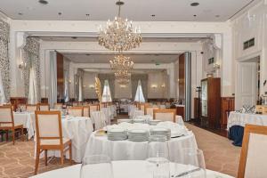 a dining room with white tables and chairs and a chandelier at BRISTOL Hotel Opatija in Opatija