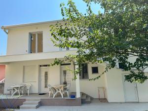 a white house with tables and chairs in front of it at Dalupada Apartments in Zgrada