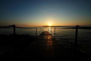 a pier with the sun setting over the water at Pietrablu Resort & Spa - CDSHotels in Polignano a Mare