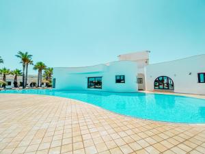 a large swimming pool with a blue building and palm trees at Pietrablu Resort & Spa - CDSHotels in Polignano a Mare