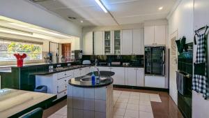 a large kitchen with white cabinets and black appliances at Zambezi Family Lodge in Victoria Falls