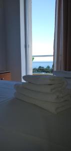 a stack of towels on a bed in front of a window at Hotel Afrodite in Dhërmi