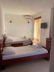 two beds in a room with a window at Hotel Afrodite in Dhërmi