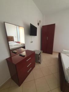 a bedroom with a dresser and a mirror and a bed at Hotel Afrodite in Dhërmi