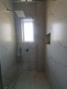 a white bathroom with a window and a shower at Hotel Afrodite in Dhërmi