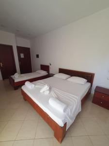 two beds in a room with white sheets and pillows at Hotel Afrodite in Dhërmi