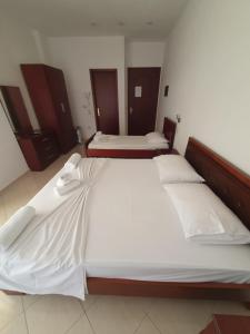 a bedroom with two beds with white sheets at Hotel Afrodite in Dhërmi