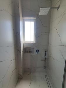a bathroom with a window and white marble walls at Hotel Afrodite in Dhërmi