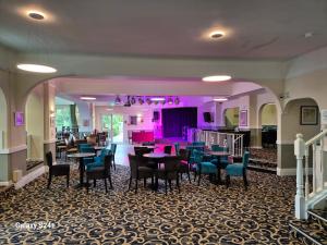 a dining room with tables and chairs and purple lighting at Trecarn Hotel in Torquay