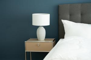 a lamp on a night stand next to a bed at SCHÖNTALHAUS City Apartments mit Balkon in Aschaffenburg