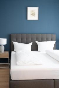 a bed with white sheets and a blue wall at SCHÖNTALHAUS City Apartments mit Balkon in Aschaffenburg