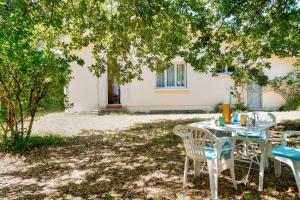 een tafel en stoelen onder een boom in een tuin bij À moins de 2km de la plage, maison pour 6 in Andernos-les-Bains