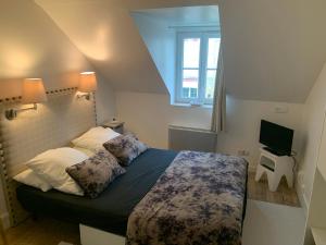ein kleines Schlafzimmer mit einem Bett und einem Fernseher in der Unterkunft Appartement à 2 pas de la plage in Cabourg