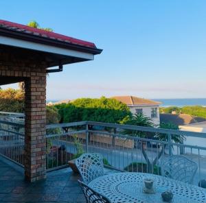 een terras met een tafel en stoelen op een balkon bij Nautilus Guesthouse in Port Elizabeth