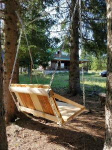 a wooden swing hanging between two trees at Vikendica Bianka u selu Uskoci in Žabljak