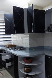 a kitchen with a counter top with a stove at Atom Height Apartments in Tema +127 photos