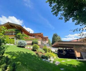 a house with a green yard with a driveway at Appartementhaus Casamarai in Saalbach Hinterglemm