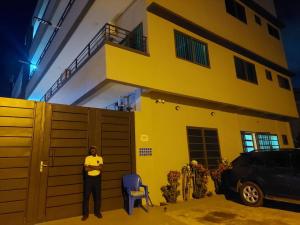 a man standing in front of a yellow house at RG Résidences in Cotonou