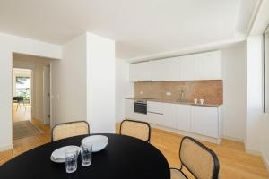 a dining room with a table and chairs and a kitchen at Azul Downtown Apartments in Coimbra
