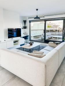 オーステンデにあるModern appartement centrum Oostende met enorm dakterras (parking beschikbaar)の大きな窓のあるリビングルーム(白いソファ付)