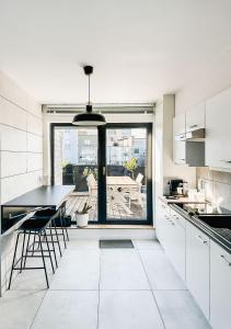 オーステンデにあるModern appartement centrum Oostende met enorm dakterras (parking beschikbaar)の白いキャビネットとテーブルと椅子のあるキッチン