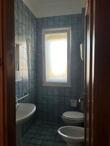 a bathroom with a toilet and a sink and a window at La casa di bruna in San Cataldo