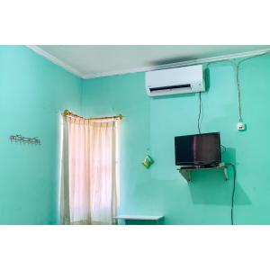 a room with a tv and a blue wall at Surya Inn Syariah Cikarang RedPartner in Bekasi +18 photos