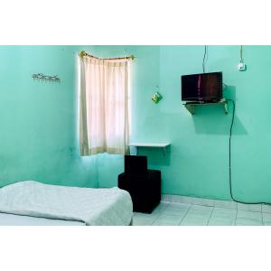 a blue room with a bed and a tv at Surya Inn Syariah Cikarang RedPartner in Bekasi