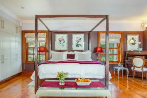 a bedroom with a canopy bed with a bowl of fruit on a table at Franschhoek Manor Luxury Boutique Guesthouse in Franschhoek +104 photos