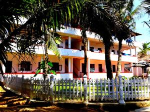 a white fence in front of a building with palm trees at Surfescape Sri Lanka in Midigama