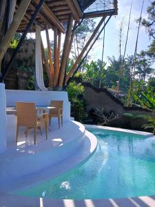 a patio with a table and chairs next to a swimming pool at Danaswari Bali Bamboo House in Selat +65 photos
