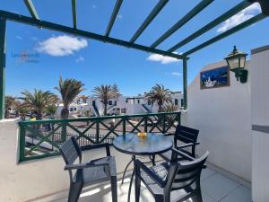 ein Tisch und Stühle auf einem Balkon mit Palmen in der Unterkunft Vivienda Vacacional Casa Mar y Volcan Vista mar Piscina Playa 5 min Wifi in Puerto del Carmen