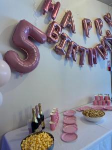 une table avec une pancarte pour une fête avec des bouteilles de vin dans l'établissement Guest House Pilsētnieki, à Slampe