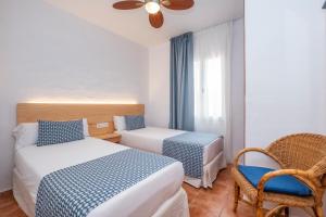 a hotel room with two beds and a chair at Comitas Tramontana Park in Fornells