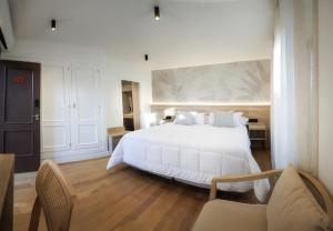 a bedroom with a large white bed and two chairs at Casa da Praza in Lobios