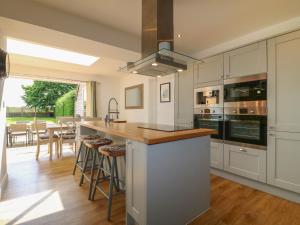 une cuisine avec des placards blancs et un îlot avec des tabourets de bar dans l'établissement Lavender Cottage, à Bourne
