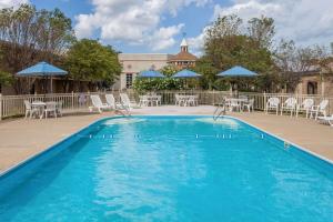 a swimming pool with chairs and tables and umbrellas at Ramada by Wyndham Hammond Hotel & Conference Center in Hammond