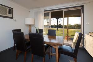 a dining room with a wooden table and chairs at Harkham Lodge in Pokolbin